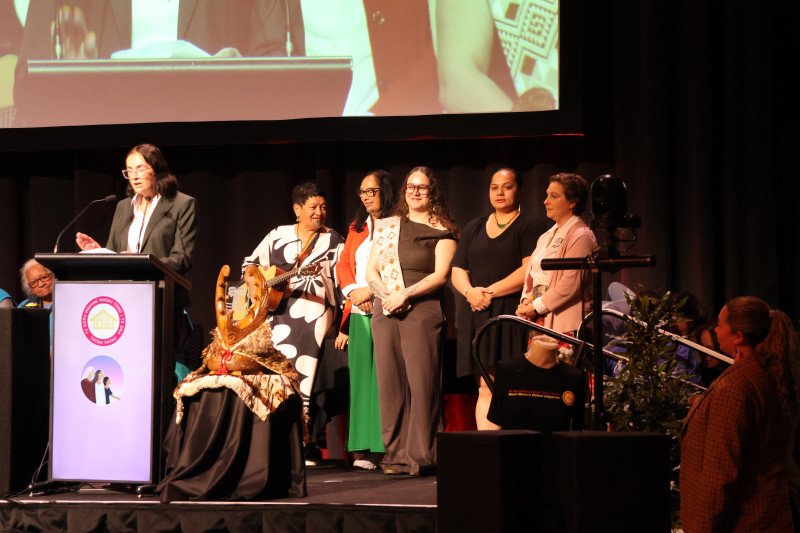 Dr Charlotte Severne, supported by kaimahi on stage during her speech.